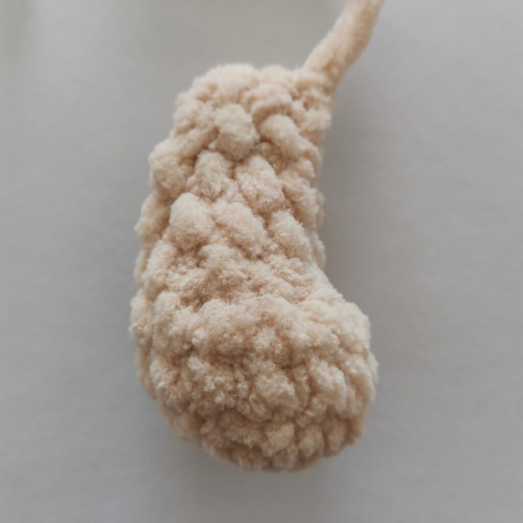 Close-up of a crocheted plush bunny leg made with chunky cream-colored yarn
