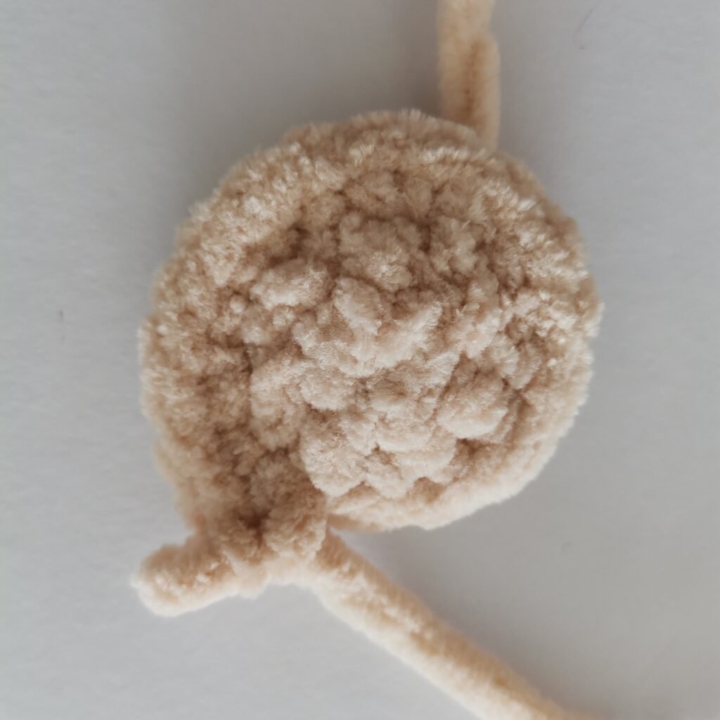 Close-up of a small part of cream-colored crochet bunny body made with soft plush yarn.