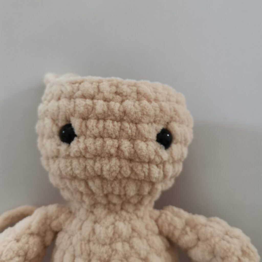Close-up of a head of cream-colored crochet bunny made with soft plush yarn.