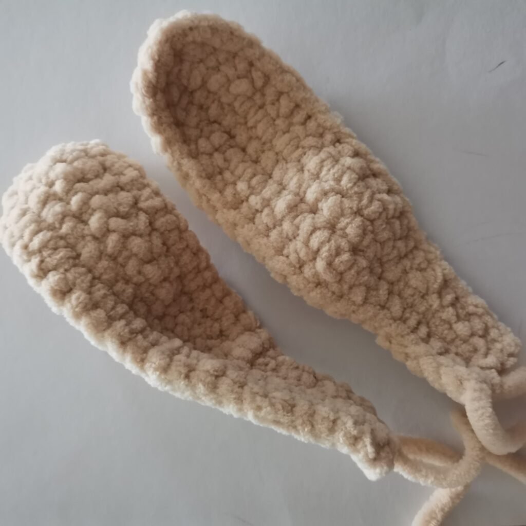 Close-up of a ears of cream-colored crochet bunny made with soft plush yarn.