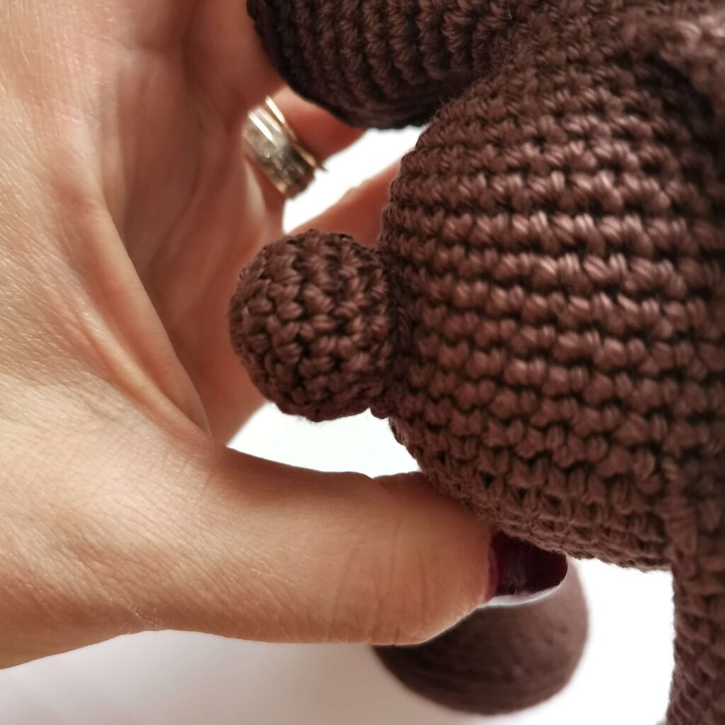 Sewing tail to the body of crocheted amigurumi teddy bear.