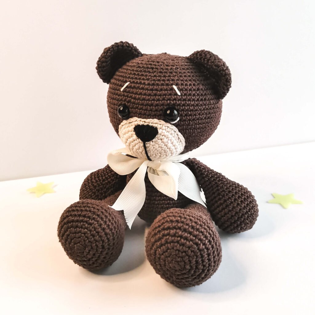 Handmade sitting amigurumi bear toy made with dark brown yarn, step by step free crochet tutorial.
