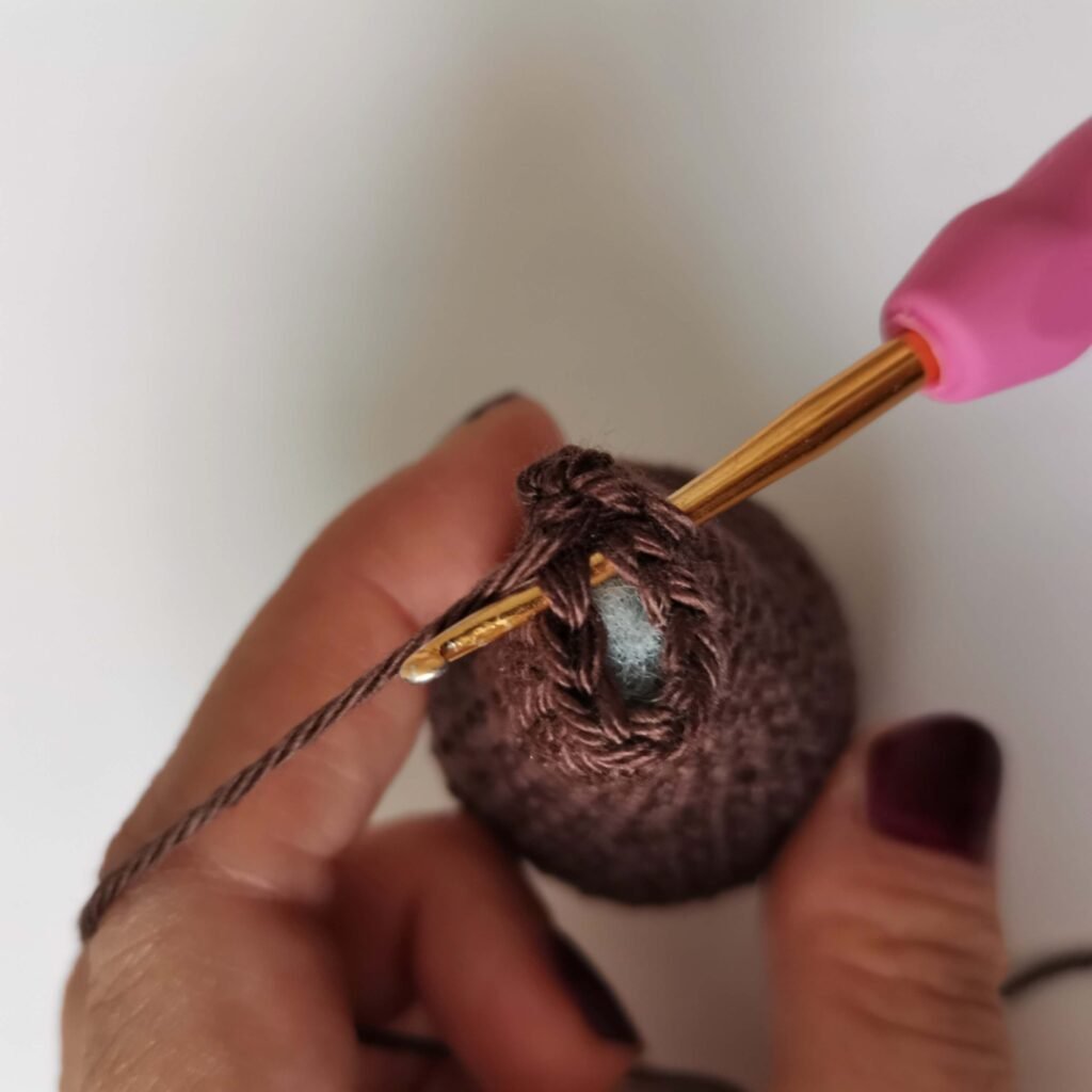 Close up view of brown amigurumi bear body being worked with a pink crochet hook by EmmaS Dolls