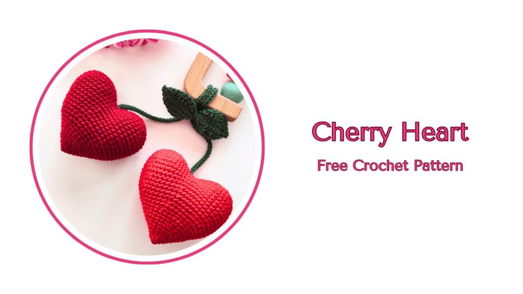 Two bright red amigurumi hearts joined by a green crochet stem and leaves, created using the free crochet heart cherry pattern.