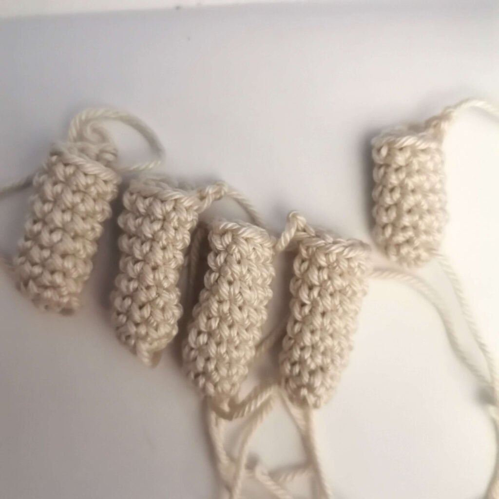Five separate crocheted fingers held in hand for the crochet stitched hand pattern process.