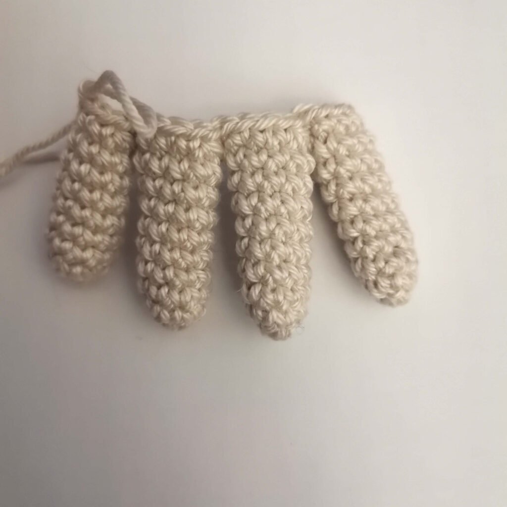 Four crocheted fingers joined together to form the palm of the amigurumi hand.