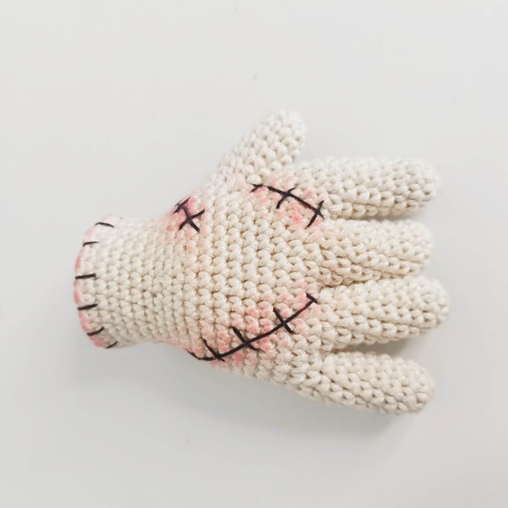 Front palm of the crocheted stitched hand with embroidered scar details and shading.