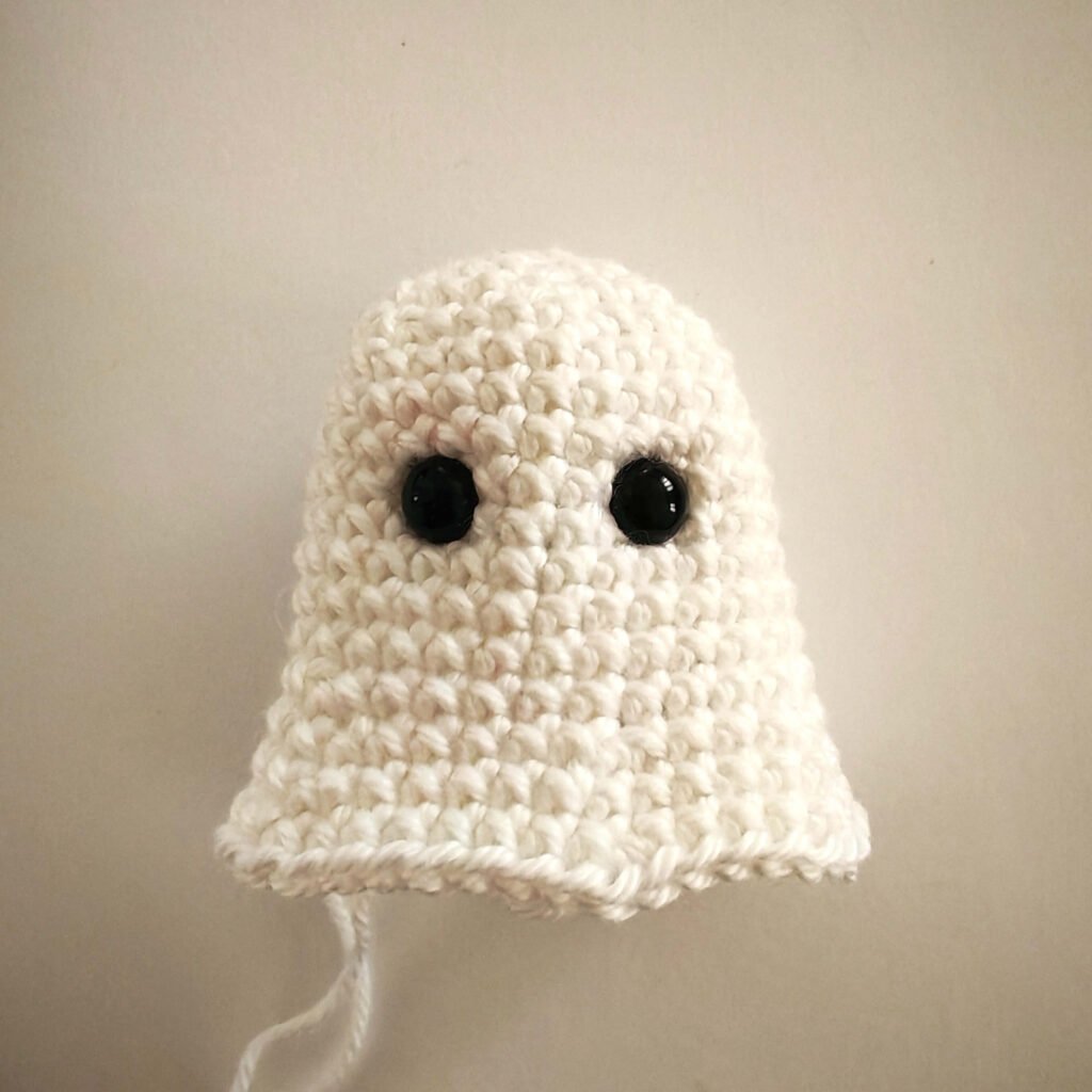 Work-in-progress white crochet ghost body with black safety eyes inserted.
